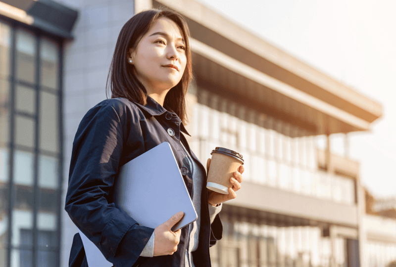 a woman holding a laptop and a coffee cup