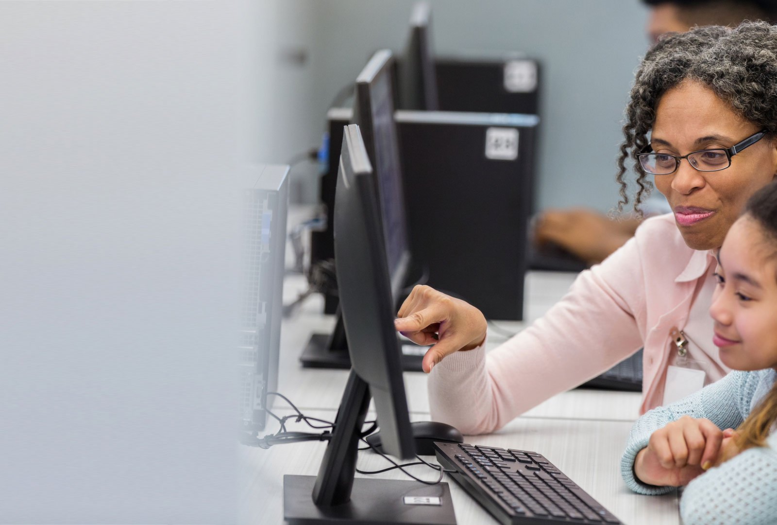 teacher/parent pointing to computer screen which the kid is using