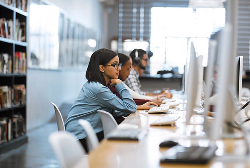 3 individuals studying/working in a library setting