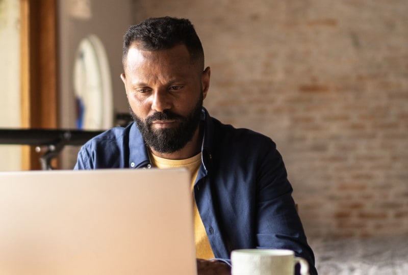 Calm man sat behind a laptop.