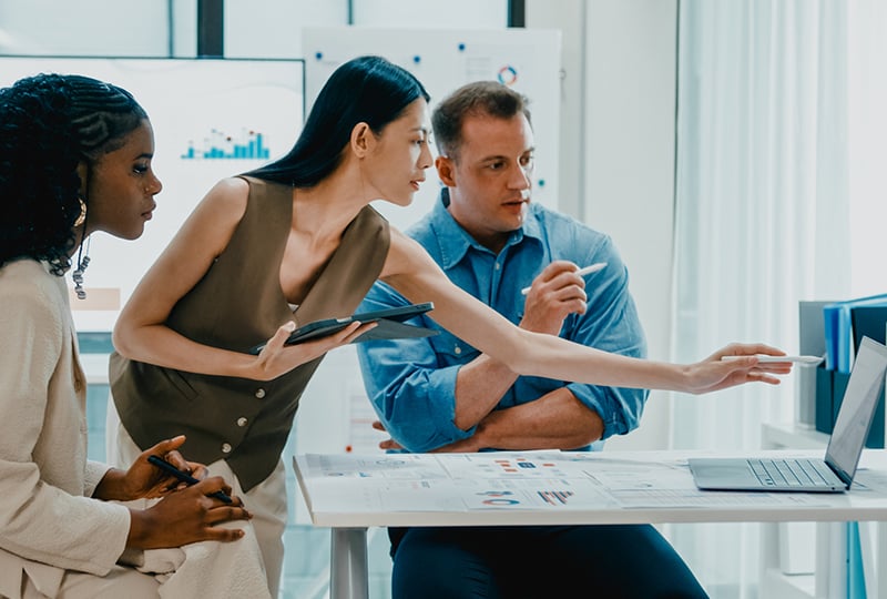 Group of people looking at a laptop in a modern office.