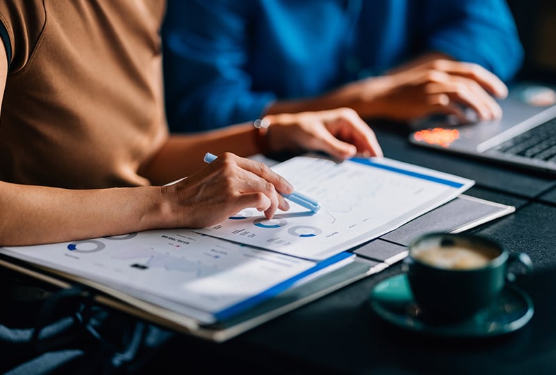 Two people analyzing data printed out on a table.