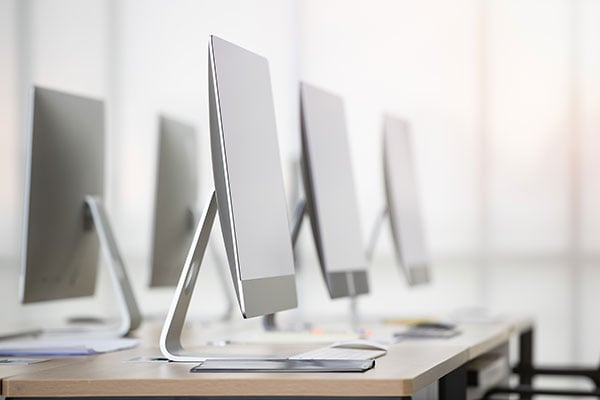 Row of modern desktop computers lined up on a long desk