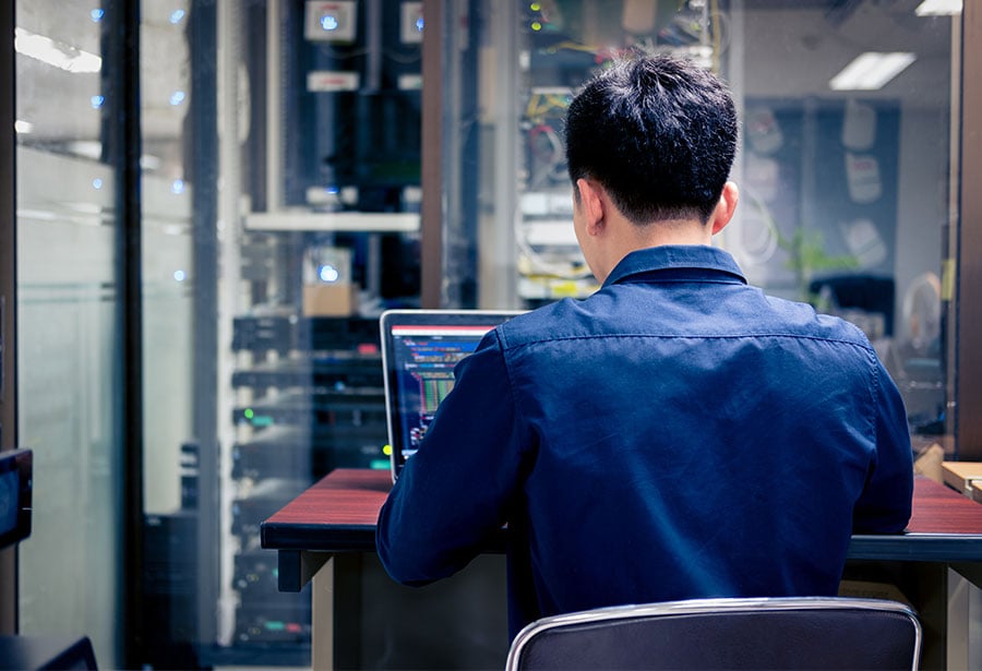 a man in it working on a laptop computer shot from behind