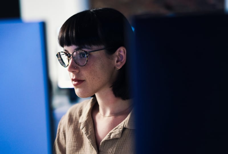 Woman wearing glasses looking intently at a computer display.