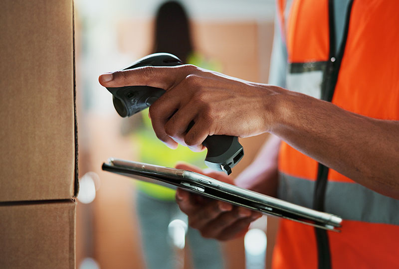 a worker is scanning the label on a box into a rugged mobile device using a handheld scanner