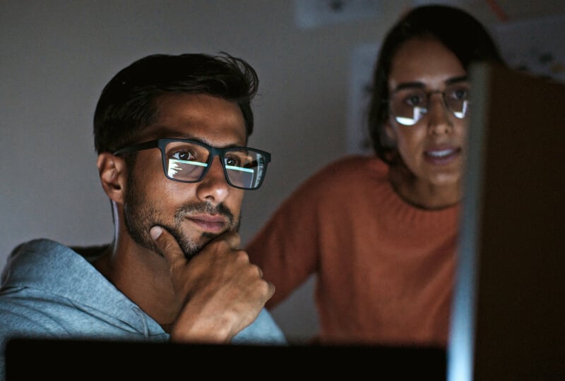 Man and woman looking towards a computer monitor.