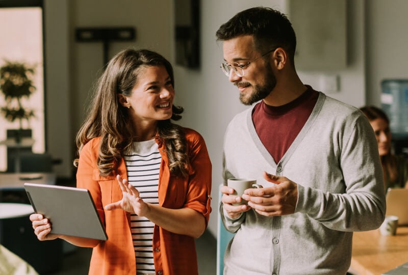 Man and woman discussing something while the woman gestures towards a tablet computer held in her hand.
